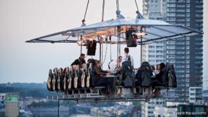 Luxury corporate event featuring a unique sky dining experience with guests seated at a suspended table above the city