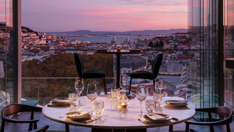 Luxury rooftop dining experience in Lisbon with panoramic city views and refined table setting at sunset