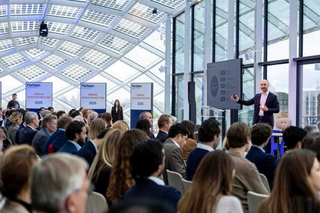 Corporate conference presentation with speaker and audience in a modern glass event venue