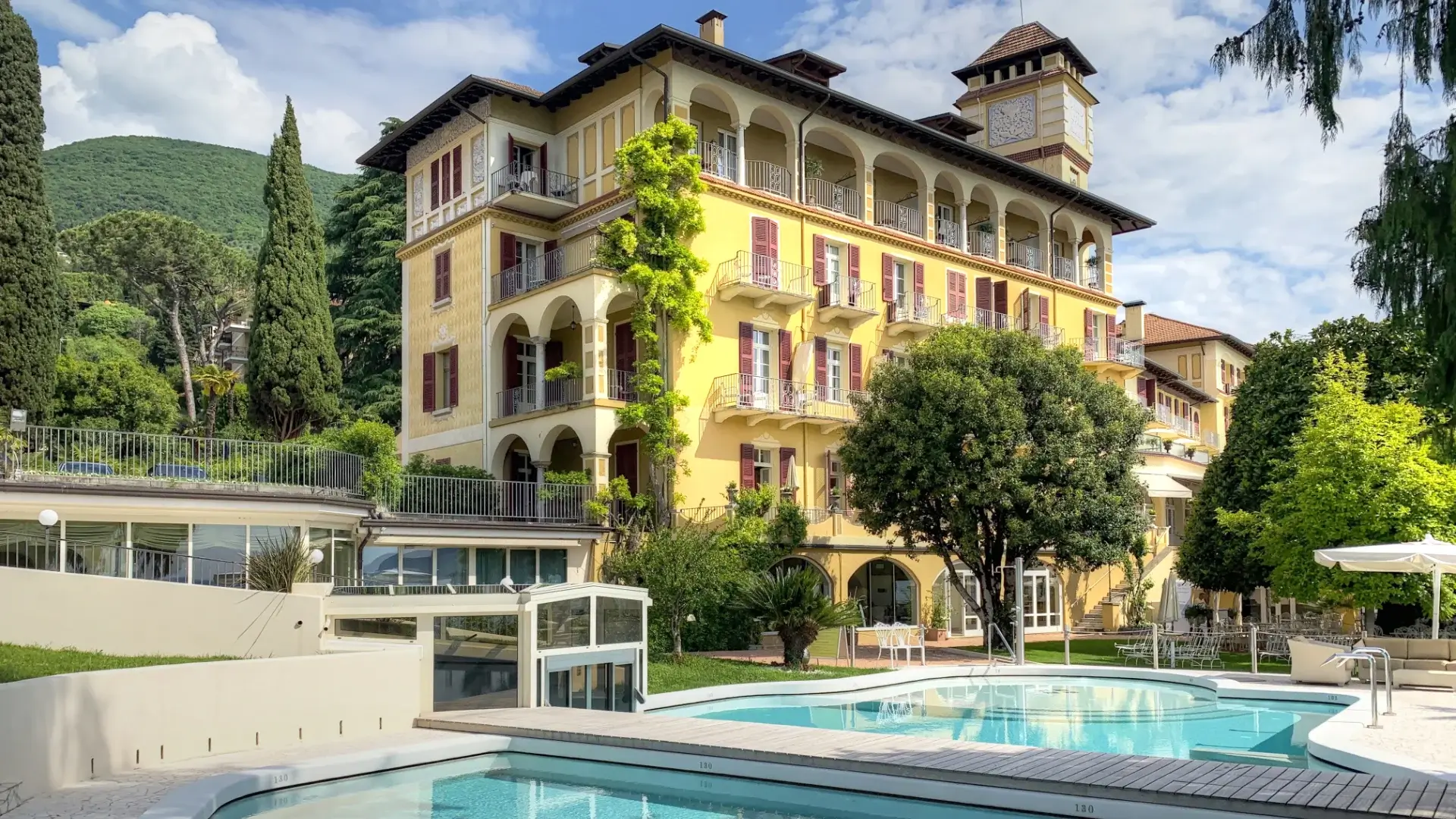 A classic Italian lakeside villa hotel with a Belle Époque yellow facade, burgundy shutters and a pool terrace — the kind of self-contained retreat property that works well as a single-venue programme, and that requires a clear decision on planning ownership before sourcing begins.