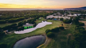 Aerial view at sunset of a golf resort on the Atlantic coast of Portugal, with umbrella pine forests, a lakeside event pavilion and the ocean on the horizon — a destination that earns its place on a retreat shortlist because it fits the brief for space, calm and direct international access, not because it appeared on a wish list first.