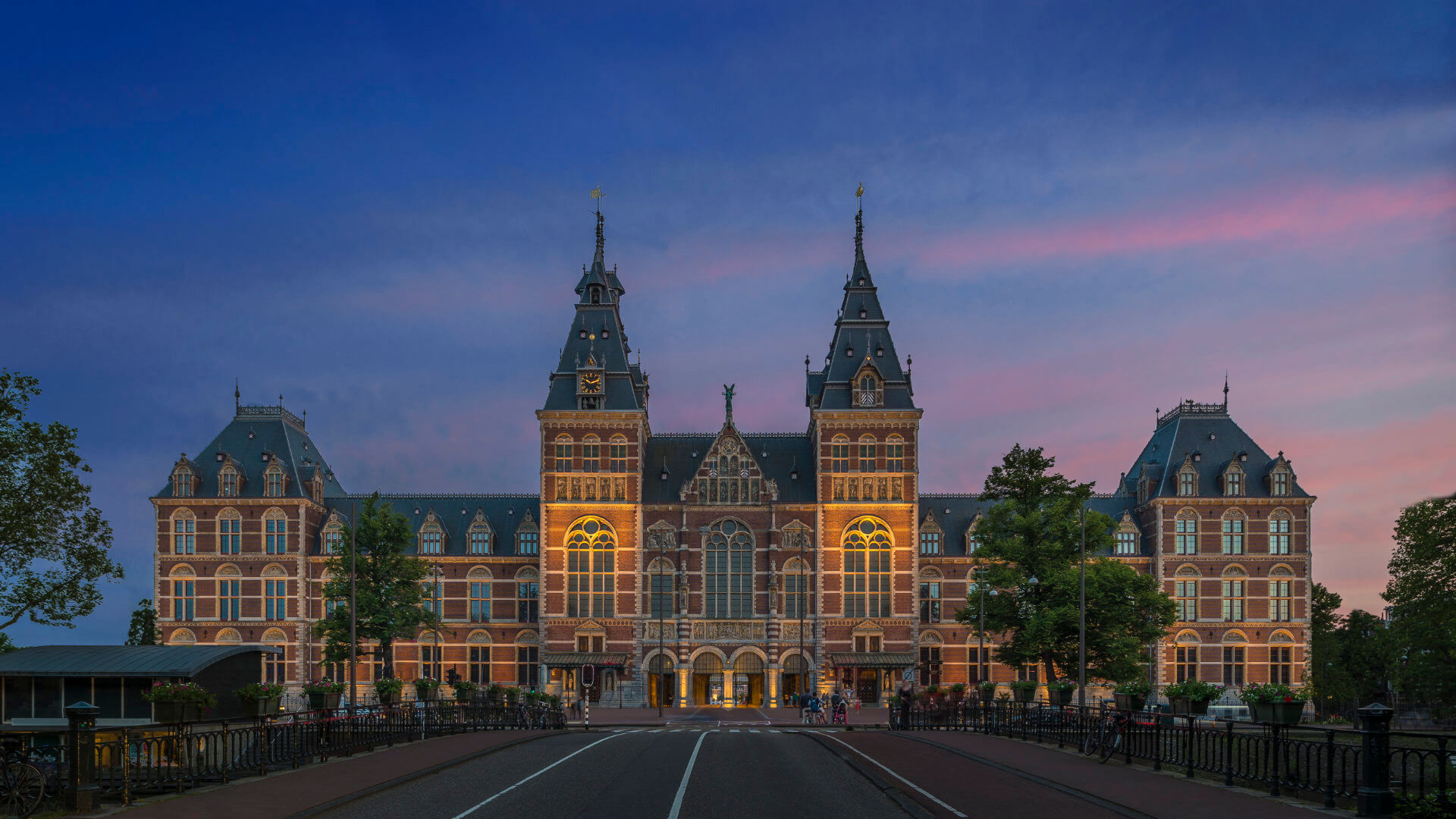 Rijksmuseum Amsterdam illuminated at dusk, seen from the museum bridge — a landmark that reflects the city's cultural depth and the value of selecting a small number of places that each contribute something distinct to a CEO programme