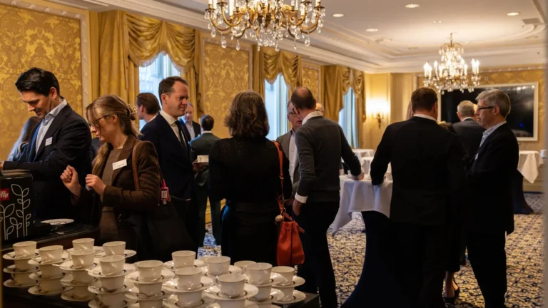 Corporate delegates networking over coffee in a gilded ballroom at the Intercontinental Amstel Hotel Amsterdam — a full-service hotel venue where one property manages both the programme space and the guest experience, simplifying planning ownership from the first conversation.