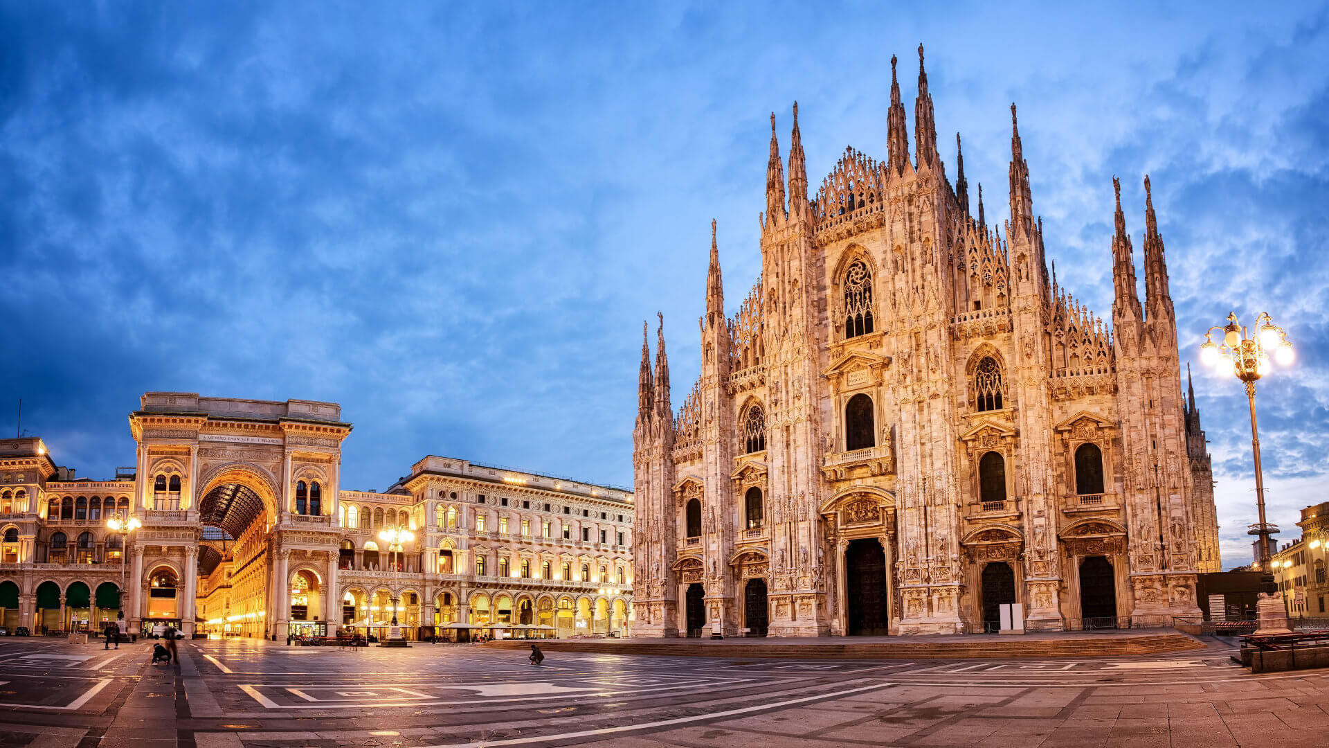 The Milan Duomo and the entrance to the Galleria Vittorio Emanuele II illuminated at blue hour — the two landmarks that stand at the intersection of six centuries of craft and commerce, and that make Milan a natural setting for a leadership programme valuing contemporary culture alongside serious business.