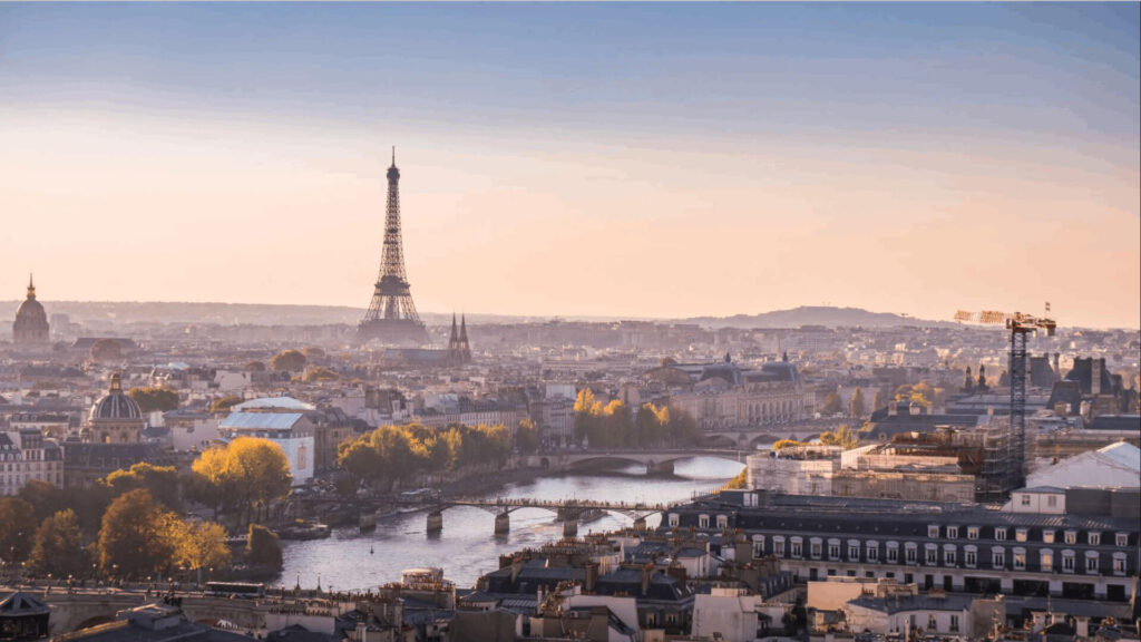 The Paris skyline at golden hour, with the Eiffel Tower rising above the Seine, autumn trees lining the riverbanks and the dome of Les Invalides to the left — the city that offers deep hotel inventory, global flight access and a remarkable concentration of art, gastronomy and heritage for a senior leadership programme.