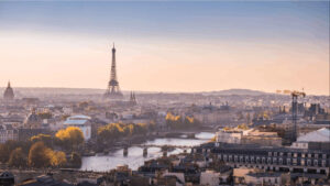 The Paris skyline at golden hour, with the Eiffel Tower rising above the Seine, autumn trees lining the riverbanks and the dome of Les Invalides to the left — the city that offers deep hotel inventory, global flight access and a remarkable concentration of art, gastronomy and heritage for a senior leadership programme.