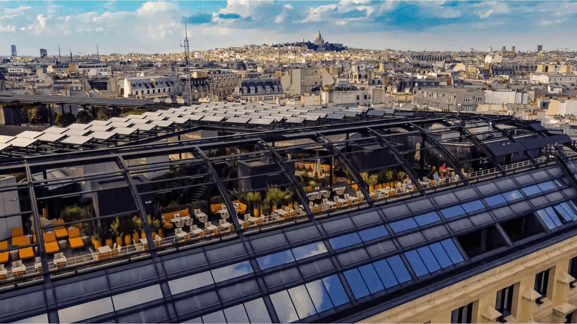 Aerial view of the Galeries Lafayette Haussmann rooftop terrace in Paris, with Sacré-Cœur on the Montmartre hillside visible on the horizon — a venue that works only when the programme logic comes first, because access, timing and permissions have to be confirmed well before the concept is committed.