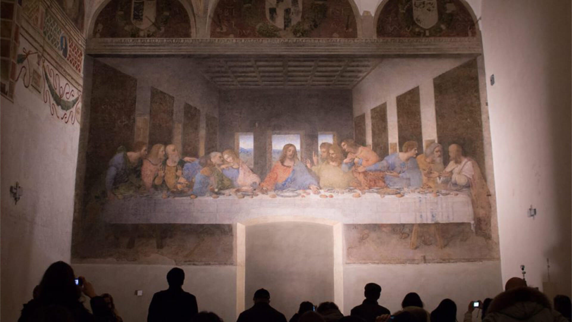 A small group viewing Leonardo da Vinci's The Last Supper in the refectory of Santa Maria delle Grazie in Milan — a timed, strictly controlled access experience that illustrates the kind of rare encounter a senior audience will travel for, and that requires a fundamentally different planning approach than a standard corporate event.